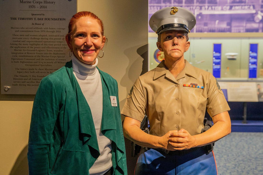 Christinia Johnson smiling and standing next to her cast figure at the National Museum of the Marine Corps.
