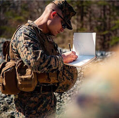 Photo of combat artist CJ Baumann sketching in the field.