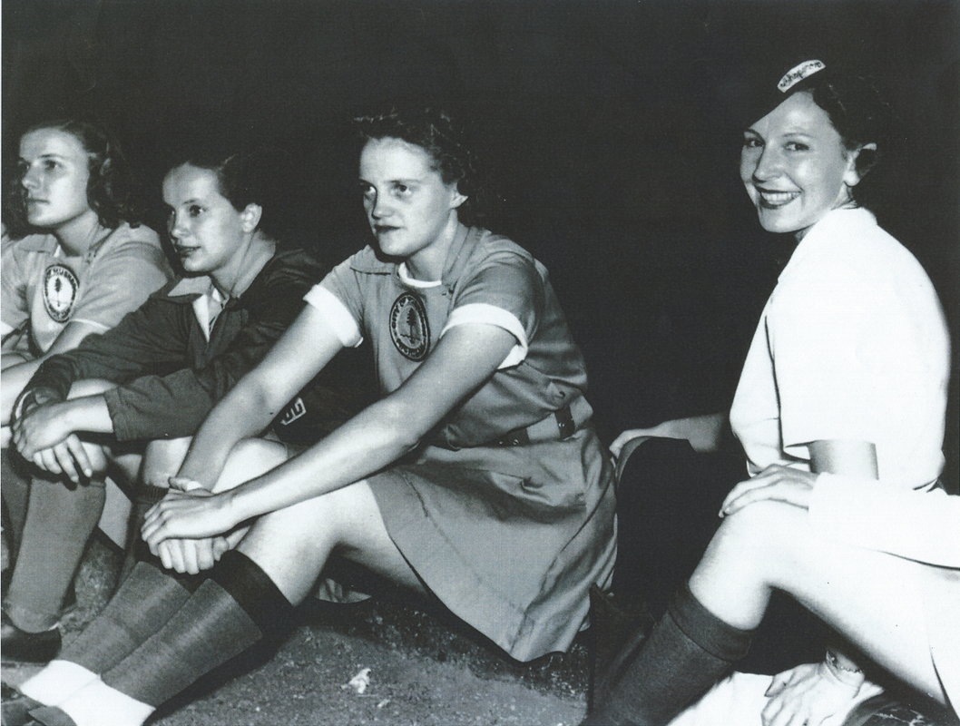 A black and white photo of Helen Hannah Campbell sitting on ground with women baseball players. 